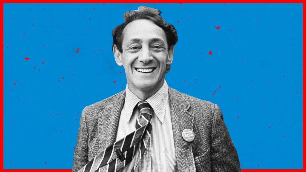 Black and white portrait of Harvey Milk, wearing a suit, tie, and a "Harvey Milk" pin, against a blue background with red speckles and a red border.