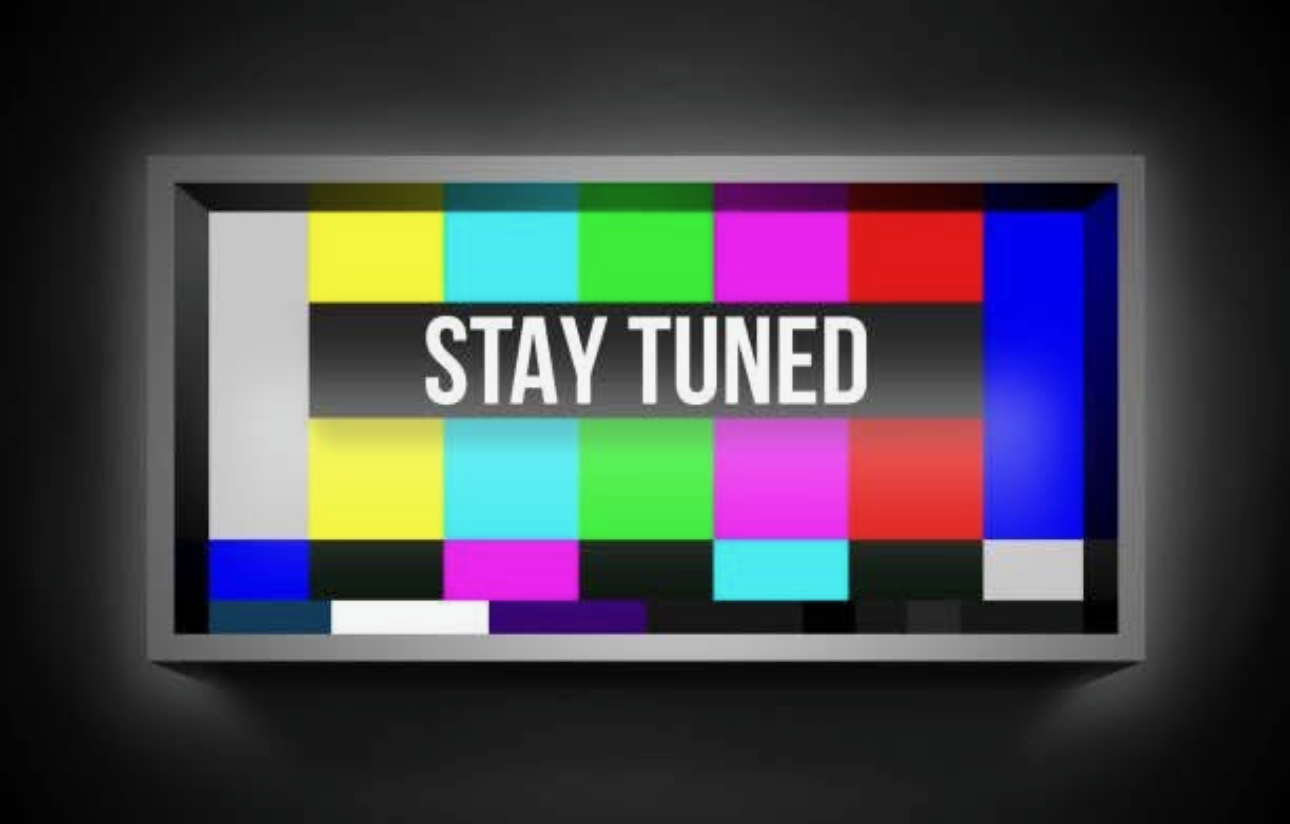A television screen displays a test pattern with the words "STAY TUNED" in white text on a dark gray bar.